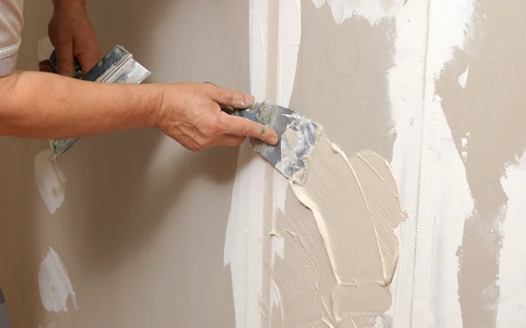 Professional applying joint compound to drywall seams during wall repair